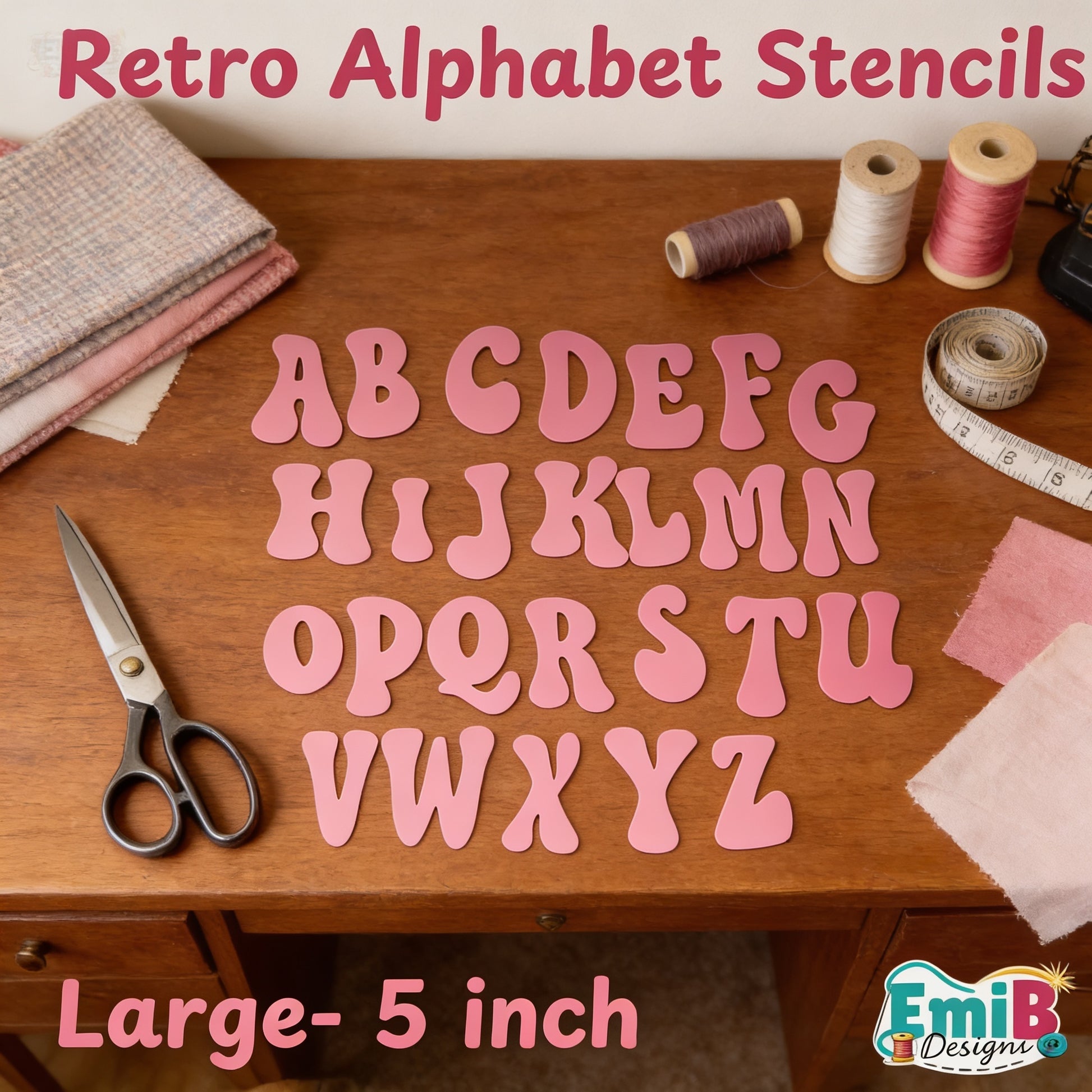 A collection of pink alphabet stencils arranged on a wooden surface, along with sewing materials such as spools of thread and fabric.
